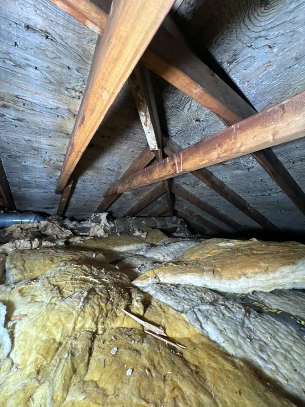 Old, compressed fiberglass insulation between attic rafters