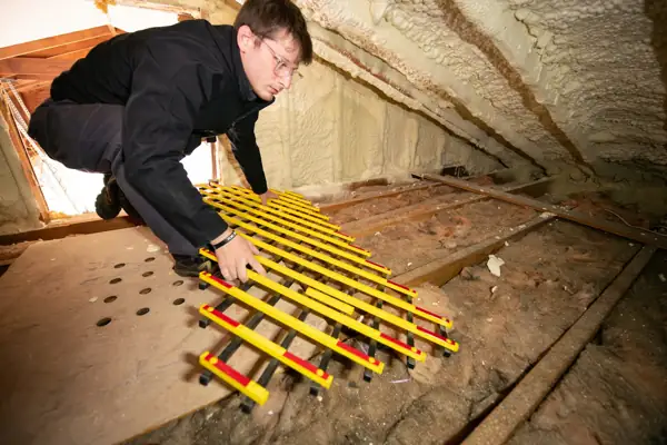 Technician crouching in an attic during an insulation job