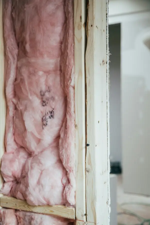 Pink fiberglass batt insulation fitted between wall studs