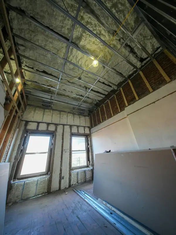 Top-floor room with spray foam insulation on walls and ceiling framing