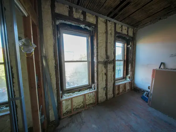 Spray foam insulation filling wall cavities around two windows