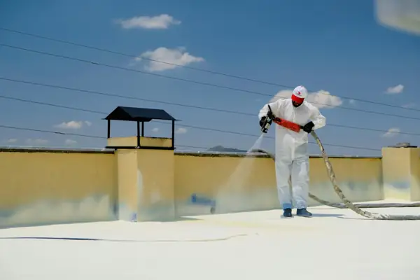 Worker in protective suit spraying a foam roof coating