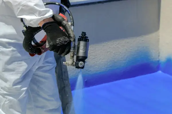Close-up of a spray foam gun applying foam to a surface