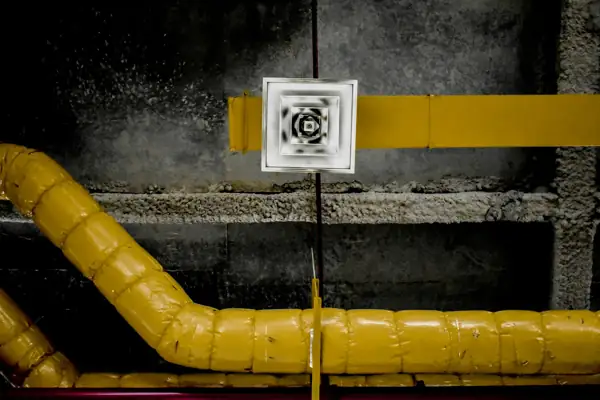 Insulated yellow pipe running beside a ceiling air diffuser