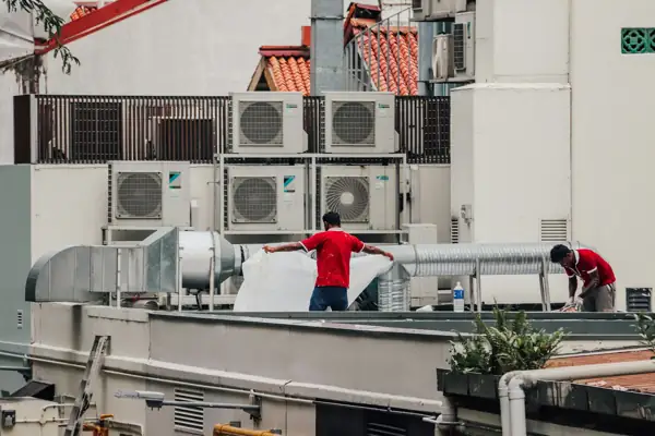 Technicians working among rooftop condensers and ductwork