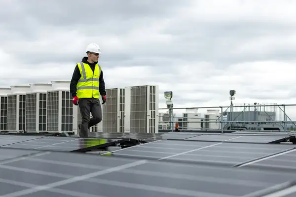 Technician in a safety vest inspecting rooftop HVAC equipment