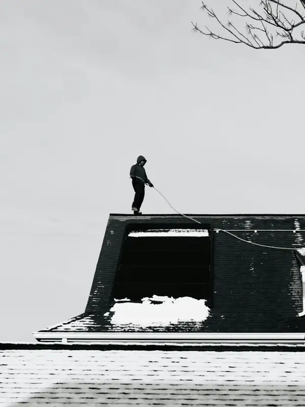 Worker on a rooftop with a line during chimney service