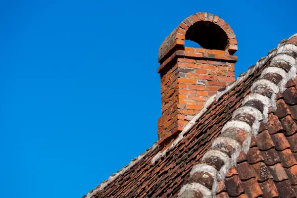 Red brick chimney with an arched cap on a tiled roof
