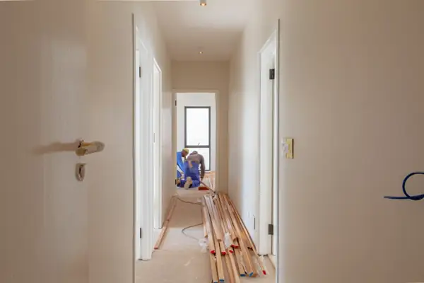 Contractors working on the floor of an apartment hallway