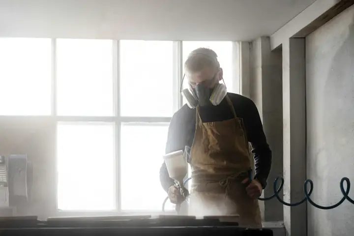 Technician in a respirator and protective apron working indoors