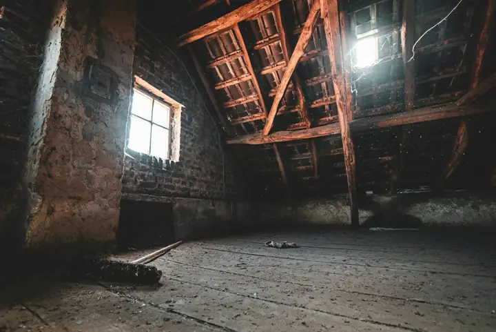Empty dim attic with a small window and exposed rafters