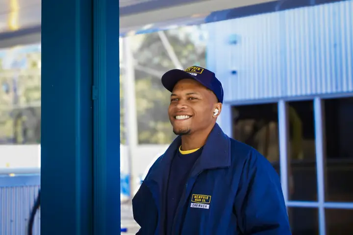 Smiling HVAC technician in uniform outside a building